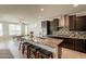 Open-concept kitchen featuring dark cabinets, granite countertops, and a center island with seating at 2543 W Rabjohn Rd, Phoenix, AZ 85085