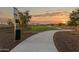 Scenic community walking path featuring lush green spaces, pet waste station, and sunset views at 25467 W Graham Trl, Buckeye, AZ 85326
