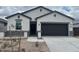 Charming single-story home featuring a stucco facade, dark gray accents, a two-car garage, and a low-maintenance front yard at 25479 W Graham Trl, Buckeye, AZ 85326