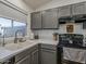 Close-up of a kitchen sink with gray cabinets and stainless steel appliances, complemented by wood-look tile flooring at 2550 E Caballero St, Mesa, AZ 85213
