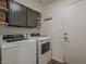 Laundry room with modern white washer and dryer and gray upper cabinets at 2550 E Caballero St, Mesa, AZ 85213