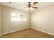 Neutral bedroom featuring a window, ceiling fan, and plush carpeting at 3554 W Aire Libre Ave, Phoenix, AZ 85053