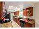 Galley kitchen featuring granite countertops, wood cabinets and modern appliances under a skylight at 3554 W Aire Libre Ave, Phoenix, AZ 85053