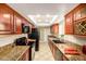 Galley kitchen featuring granite countertops, wood cabinets and modern appliances under a skylight at 3554 W Aire Libre Ave, Phoenix, AZ 85053