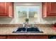 Close-up of the kitchen sink with granite counters and wood cabinets, with backyard view at 3554 W Aire Libre Ave, Phoenix, AZ 85053