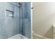 Modern blue-tiled bathtub-shower featuring a rainfall shower head and recessed storage at 3824 W Carol Ave, Phoenix, AZ 85051