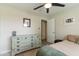 Comfortable bedroom with a ceiling fan, neutral wall color, and a distressed dresser at 3824 W Carol Ave, Phoenix, AZ 85051