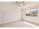 Neutral bedroom featuring a ceiling fan, tile flooring, and a window with bars at 5529 W Virginia Ave, Phoenix, AZ 85035