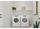 Clean and functional laundry room featuring modern appliances, built-in shelving, and minimalist decor at 7404 W Buckhorn Trl, Peoria, AZ 85383