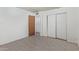 A bedroom with gray wood-look tile floors and white walls featuring an open door and a closet with sliding doors at 8033 N 56Th Ave, Glendale, AZ 85302