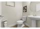 Well-lit half bathroom featuring a pedestal sink, updated fixtures, decorative artwork and a comfort height toilet at 8343 E Irwin Ave, Mesa, AZ 85209
