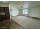 Open-concept living room with neutral carpet, ceiling fan, and natural light from the large windows at 10231 E Illini St, Mesa, AZ 85208