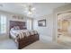This is a main bedroom with a dark wood platform bed, ceiling fan, and neutral colored carpet at 11012 E Knowles Ave, Mesa, AZ 85209