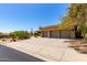 A large driveway leads to the three-car garage of this desert home, surrounded by mature landscaping at 16562 N 109Th Way, Scottsdale, AZ 85255
