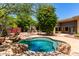 Relaxing backyard pool nestled among rocks, mature trees, and desert plants providing shade and beauty at 16562 N 109Th Way, Scottsdale, AZ 85255