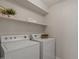 Bright laundry room with white washer and dryer, complemented by shelving for storage and organization at 1761 E Countrywalk Ln, Chandler, AZ 85225