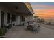 Covered patio with outdoor dining table, landscaped backyard, and ceiling fan at 18161 N 63Rd Ln, Glendale, AZ 85308