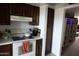 Kitchen area with white appliances, wooden cabinetry, and adjacent shelving in the next room at 1927 E Hampton Ave # 208, Mesa, AZ 85204