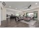 Bright open-concept living room with a large gray sectional, hardwood floors, and view of the modern kitchen at 22858 E Silver Creek Ln, Queen Creek, AZ 85142