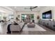 Open-concept living room with sleek ceiling fan, TV console, plush gray sectional, and sliding door to backyard at 22858 E Silver Creek Ln, Queen Creek, AZ 85142