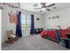 A colorful bedroom featuring neutral walls, gray carpet, a ceiling fan, basketball hoop and a window with blue curtains at 26116 N Thornhill Dr, Peoria, AZ 85383