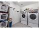 Functional laundry room with modern washer and dryer, plus shelving and storage baskets at 26116 N Thornhill Dr, Peoria, AZ 85383