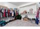 A walk-in closet with neutral walls, carpeting, built-in shelving and racks with an array of storage options at 26116 N Thornhill Dr, Peoria, AZ 85383
