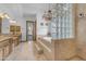 Luxurious bathroom with a soaking tub, glass block wall, and elegant chandelier at 3217 N Piedra Cir, Mesa, AZ 85207