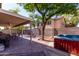 Spacious backyard featuring a covered patio, brick pavers, a mature shade tree, and a relaxing hot tub at 424 W Midland Ln, Gilbert, AZ 85233
