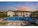 Backyard pool with travertine decking, outdoor grill, and lounge furniture under a colorful sky at 5226 S Fairchild Ln, Chandler, AZ 85249