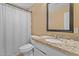 Bathroom features a toilet, shower with white curtain, and granite countertop with a white sink and dark framed mirror at 5519 W Campbell Ave, Phoenix, AZ 85031