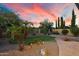Beautiful backyard featuring a manicured lawn, desert landscaping, and a stone paver walkway at sunset at 8234 E Inca St, Mesa, AZ 85207