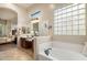 Bright bathroom featuring double vanity, soaking tub, glass block window, and tile flooring at 8234 E Inca St, Mesa, AZ 85207