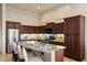 A spacious kitchen features dark wood cabinetry, stainless steel appliances, and a large granite island with bar seating at 8234 E Inca St, Mesa, AZ 85207