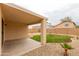 Covered patio overlooks a landscaped backyard with green grass, decorative rock and palm tree at 9319 W Crown King Rd, Tolleson, AZ 85353