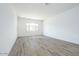 Bright, open bedroom featuring wood-look tile flooring, white walls, and a window with a view at 10022 S 37Th Ave, Laveen, AZ 85339