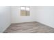 Bright bedroom showcasing wood-look tile flooring, white walls, and a window with a view of the backyard at 10022 S 37Th Ave, Laveen, AZ 85339