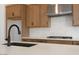 Close up view of sink, light countertops, wood cabinets, stainless vent hood, and gas cooktop at 10022 S 37Th Ave, Laveen, AZ 85339