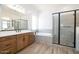 Modern main bathroom featuring wood-look tile, double vanity, soaking tub, and glass enclosed shower at 10022 S 37Th Ave, Laveen, AZ 85339