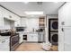 Well-lit kitchen featuring modern appliances, white cabinets, and laminate floors, maximizing space with washer and dryer at 13039 N 19Th Ave, Phoenix, AZ 85029