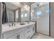Elegant bathroom featuring double sinks, modern lighting, and a walk-in shower with glass enclosure at 14634 W Wethersfield Rd, Surprise, AZ 85379