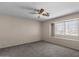 Bedroom has neutral walls, carpeted floor, a ceiling fan, and a window overlooking the neighborhood at 15829 S 13Th Pl, Phoenix, AZ 85048