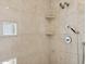 Luxurious walk-in shower with travertine tile and a hand-held shower head and corner shelving at 17030 N 57Th St, Scottsdale, AZ 85254