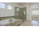 Luxurious bathroom with jetted tub, glass shower, tiled accents, and large windows at 17303 N 98Th Pl, Scottsdale, AZ 85255