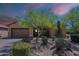 Tan home with a desert xeriscape front yard featuring various bushes, cactus and trees at 17303 N 98Th Pl, Scottsdale, AZ 85255