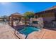 Inviting pool area with a cozy spa, covered seating, a stone fireplace, and lush landscaping at 17303 N 98Th Pl, Scottsdale, AZ 85255