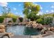Private backyard oasis boasting a pool with a rock waterfall, lush landscaping, and an outdoor living space at 18500 N 95Th St, Scottsdale, AZ 85255