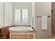 Bright bathroom featuring a soaking tub with decorative tile accents, white shutters, and modern fixtures at 18500 N 95Th St, Scottsdale, AZ 85255