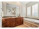 Well-lit bathroom featuring granite countertops, dark wood cabinetry, a soaking tub, and a view of the shower at 18500 N 95Th St, Scottsdale, AZ 85255