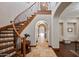 Elegant entryway with curved staircase, stone floors, wood accents, and hallway archways at 18500 N 95Th St, Scottsdale, AZ 85255
